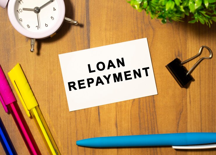LOAN REPAYMENTというテキストの名刺は、事務用品の中の木製のオフィステーブルにあります。