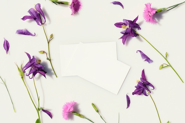 Business cards on a gray background surrounded by fresh blue and pink flowers Top view