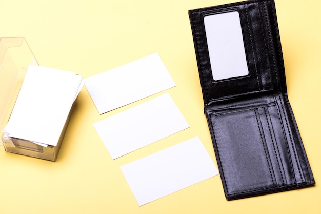 Business cards stack in card holder on yellow background. Personal presentation accessory and leather wallet in close up. Business finance and contacts concept. Cards in white color with copy space.