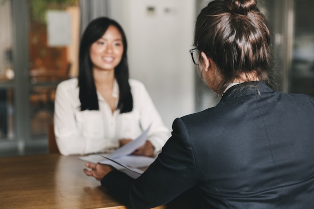 Business, career and placement concept -photo from back of businesswoman interviewing, and talking with female applicant during job interview