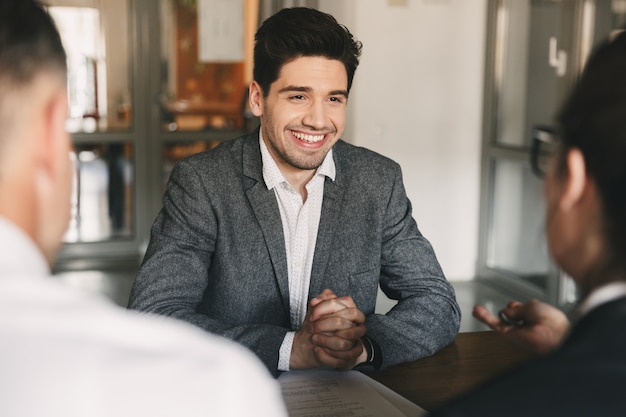 Business, career and placement concept - smiling caucasian man 30s negotiating with employees of big company, during job interview in office