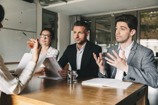 Business, career and placement concept - three executive directors or head managers sitting at table in office, and negotiating with new personnel during interview