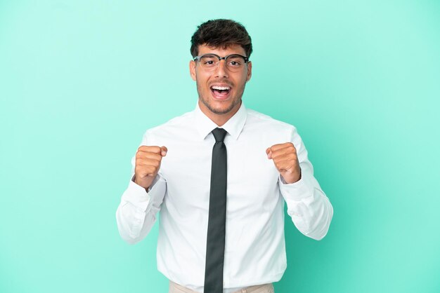 Business caucasian man isolated on blue background celebrating a victory in winner position