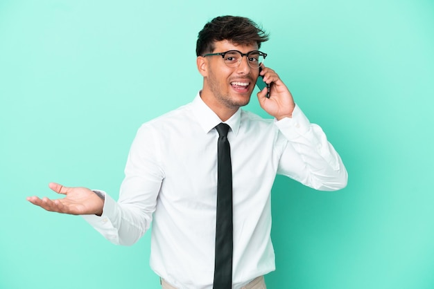 Business caucasian man isolated on blue background keeping a conversation with the mobile phone with someone