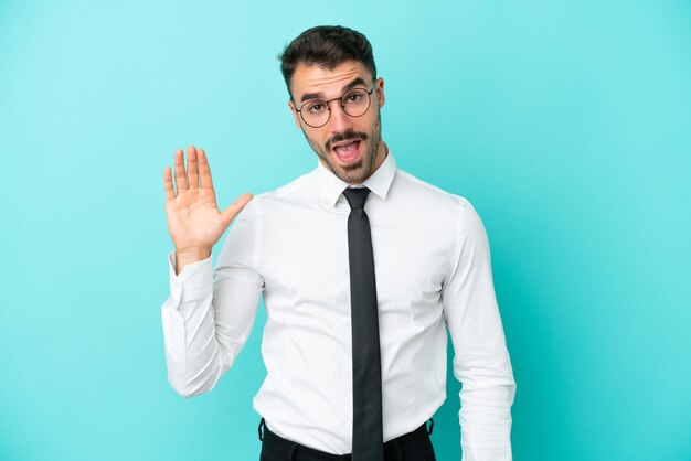 Business caucasian man isolated on blue background saluting with hand with happy expression