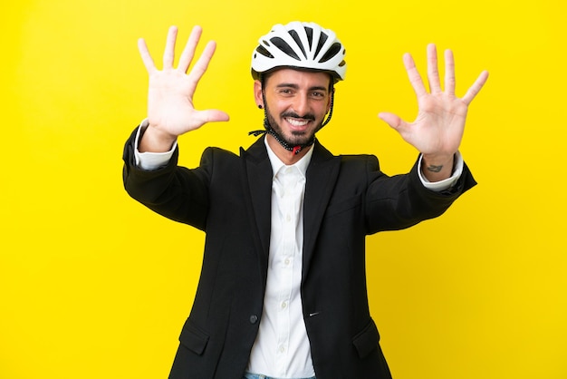 Деловой кавказец в велосипедном шлеме на желтом фоне, считая десять пальцами