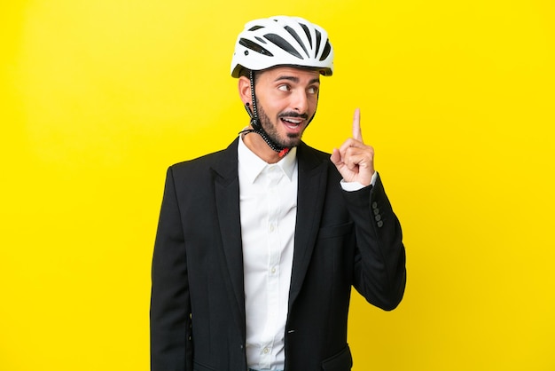 Business caucasian man with a bike helmet isolated on yellow background intending to realizes the solution while lifting a finger up