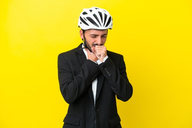 Business caucasian man with a bike helmet isolated on yellow background is suffering with cough and feeling bad