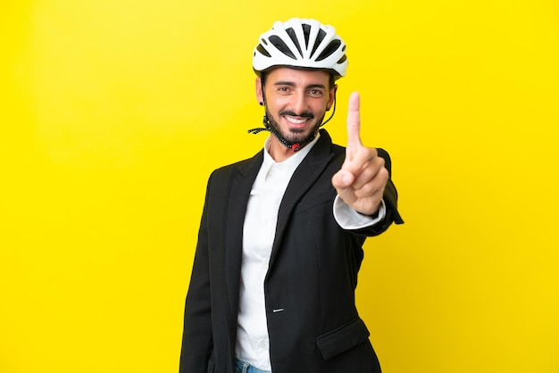 Business caucasian man with a bike helmet isolated on yellow background showing and lifting a finger