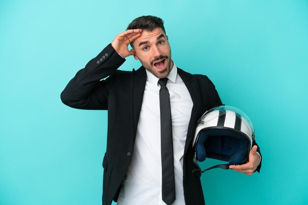 Business caucasian man with motorbike helmet isolated on blue background with surprise expression