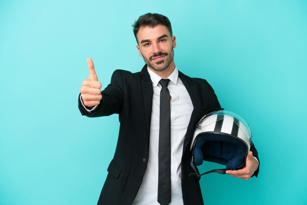 Business caucasian man with motorbike helmet isolated on blue background with thumbs up because something good has happened