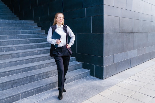 Business caucasian woman holding a laptop and outdoors surrounded by buildings