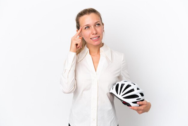 疑問と思考を持っている白い背景で隔離の自転車のヘルメットを持つビジネス白人女性