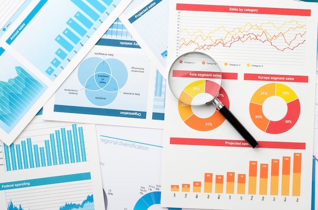 Business chart and magnifier on the desktop. The concept of analysis and determination of key information in business.