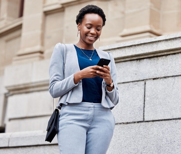 사진 스마트폰 타이핑이나 컨설턴트 미소 또는 의사소통과의 연결을 갖춘 비즈니스 도시 또는 흑인 여성 모바일 앱 이메일 또는 야외 인터넷 검색을 통해 개인 기업가 또는 휴대폰
