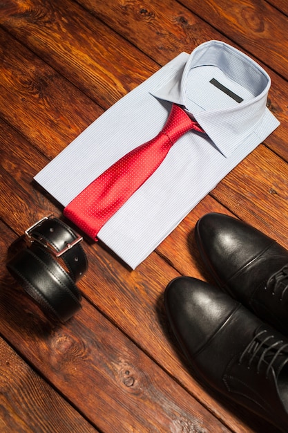 Business clothes set. White shirt red tie black leather shoes belt