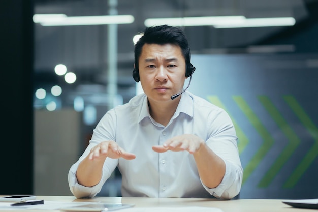 Бизнес-тренер молодой красивый азиат в наушниках с микрофоном проводит бизнес-тренинг