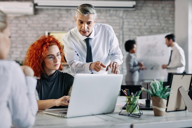 Business colleagues cooperating while working together on computer in modern office