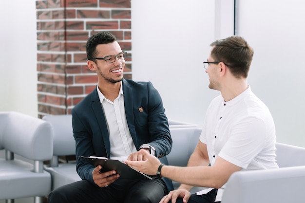 Business colleagues discussing business document sitting in office lobby. business concept