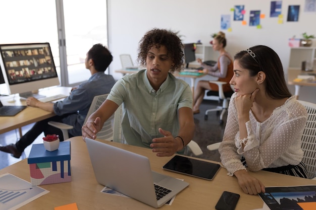 Photo business colleagues discussing over laptop in office