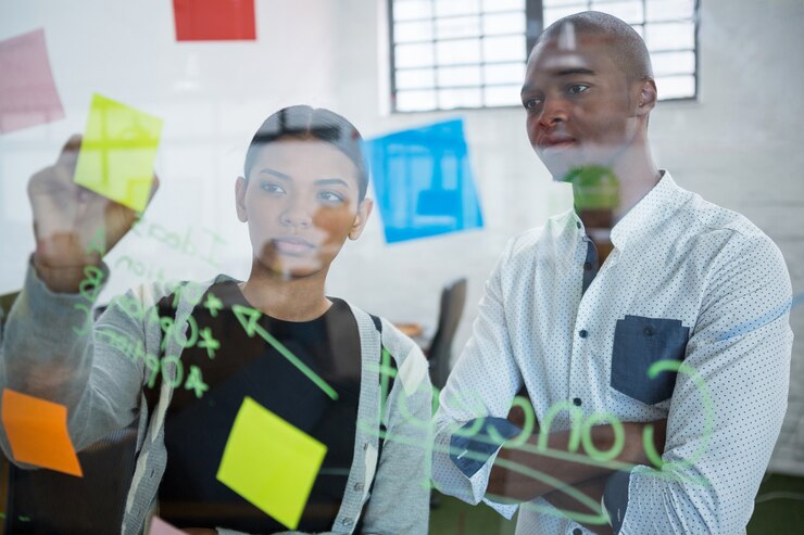Photo business colleagues reading sticky notes on glass