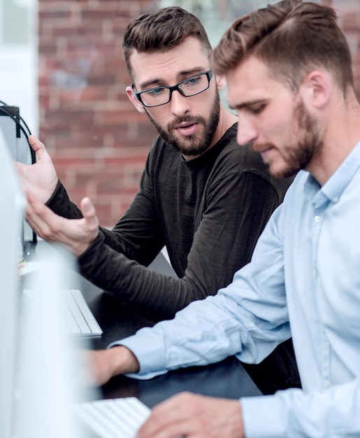 Photo business colleagues talk sitting at a computer table