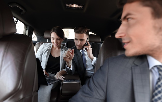 Business colleagues use a laptop to work in the car