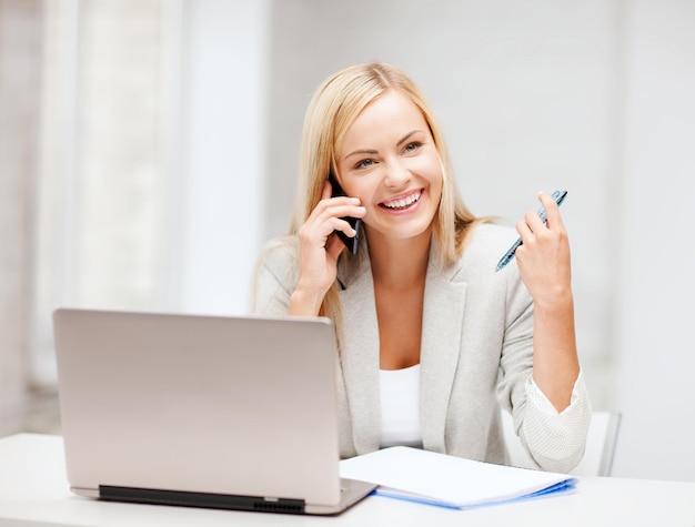 бизнес и общение - улыбающаяся деловая женщина со смартфоном в офисе