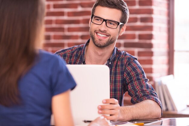 Business communication. Two business people in casual wear talking and smiling while sitting face to face at the table