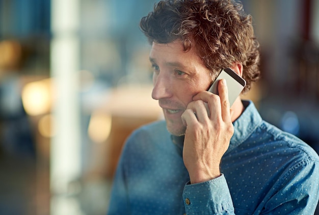 Foto comunicazioni aziendali scatto di un bell'uomo d'affari che parla sul suo telefono cellulare sul posto di lavoro