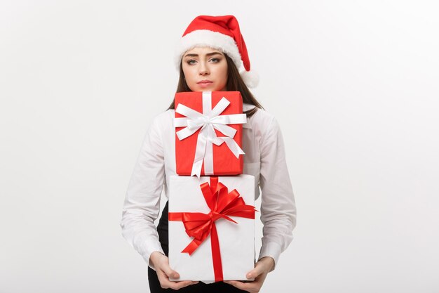 Business concept  beautiful young caucasian business woman with santa hat holding a lot of gift boxes with worry facial expression