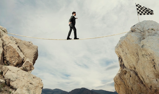 Photo business concept of businessman who overcome the problems reaching the finish line on a rope