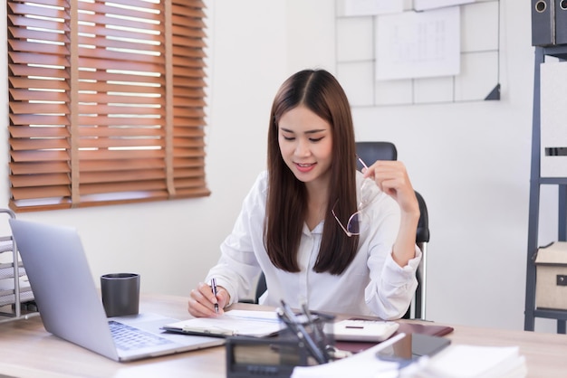 Business concept Businesswoman is hold glasses while reading and writing data on business document