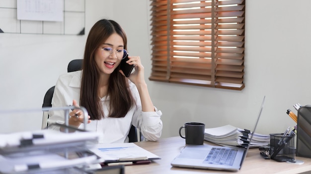 Business concept Businesswoman is talking financial data with partner on smartphone at office