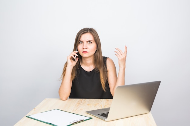 Business concept - businesswoman talking on the phone in office and working on laptop.