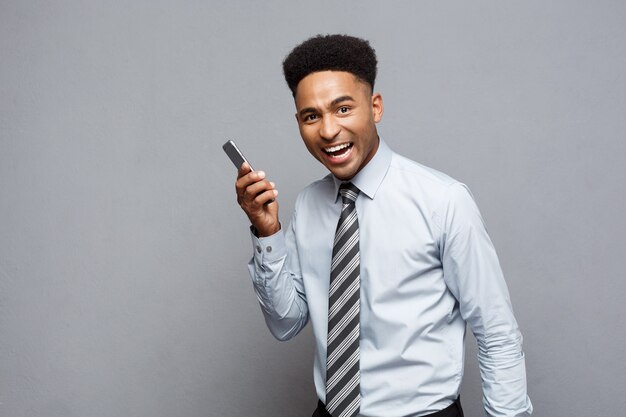 ビジネスコンセプト-クライアントと携帯電話で幸せに話している陽気なプロのアフリカ系アメリカ人ビジネスマン。