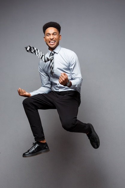 Business Concept - Full length portrait of successful african american businessman happy jumping in the office. 