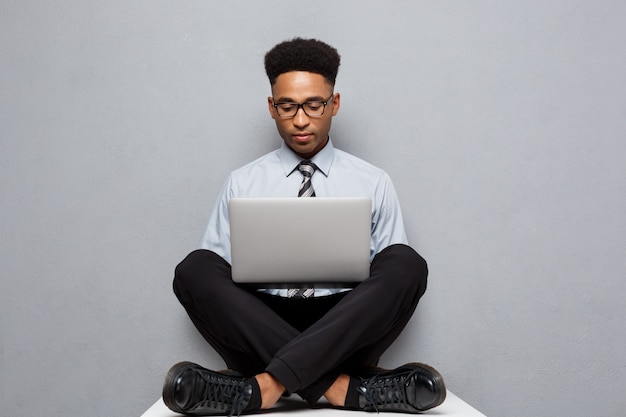 Concetto di affari - l'uomo d'affari afroamericano professionista bello felice gode di di giocare su labtop.