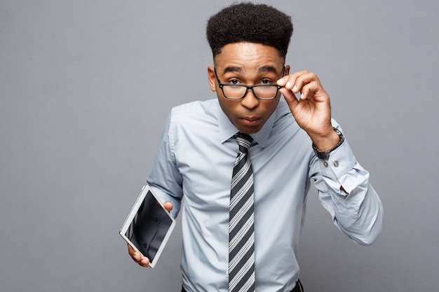 Business Concept - Happy handsome professional african american businessman holding tablet with surprising facial expression.