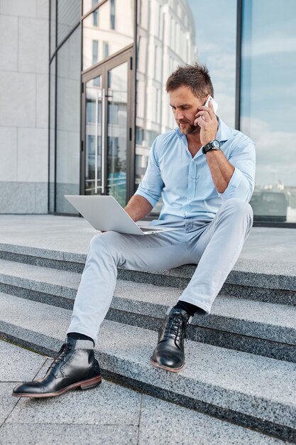 Business concept man with laptop sitting on porch of office building