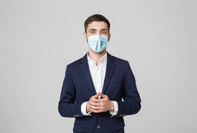 Photo business concept - portrait handsome businessman in face mask holding hands with confident face. white wall.