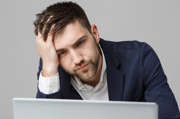 Concetto di affari - ritratto di uomo bello di affari grazioso in tuta guardando laptop. sfondo bianco.