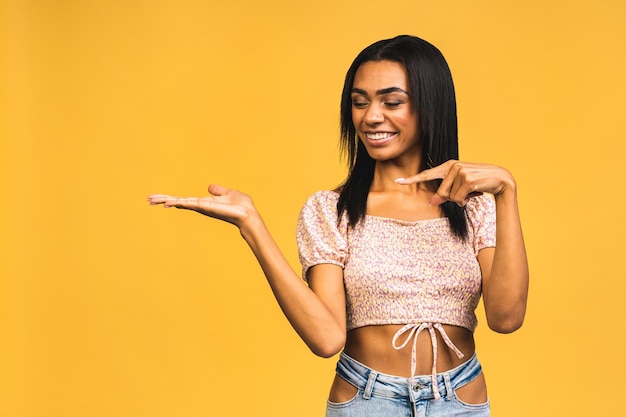 Business Concept Portret van mooie Afro-Amerikaanse zwarte jonge presenteren door hand op kant geïsoleerd op gele achtergrond te wijzen