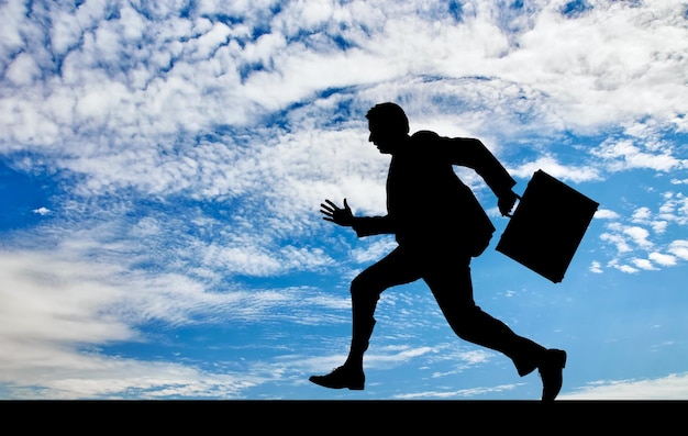 Photo business concept. silhouette of running businessman with briefcase in hand against a beautiful sky
