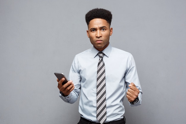 Business Concept - Stressful african american businessman shouting and screaming on mobile phone.