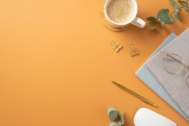 Business concept top view photo of workstation cup of coffee on wooden stand white computer mouse glasses planners gold pen binder clips and eucalyptus on isolated orange background with copyspace