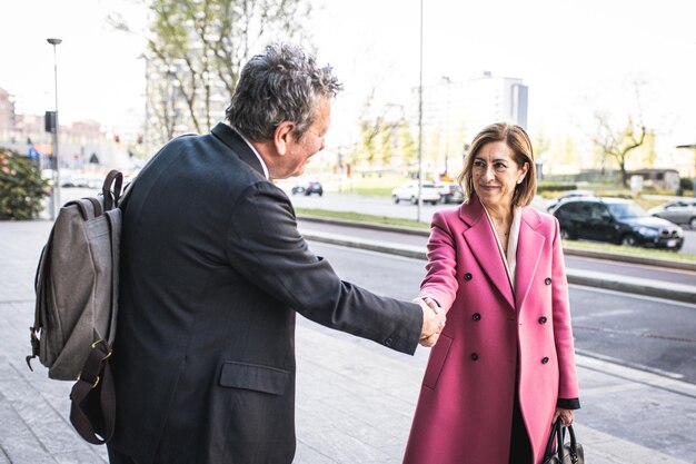 Business concept two partners shaking hands standing in front
of company office couple of business person satisfied by the
agreement successful entrepreneurs deal