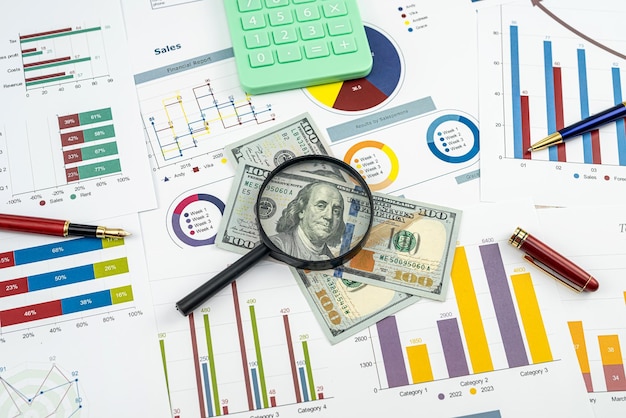 Business concept vergrootglas munt Amerikaanse dollarbiljetten rekenmachine en pen op grafieken grafieken papier