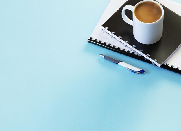 business concept with notebooks pen and cup of coffee on blue background