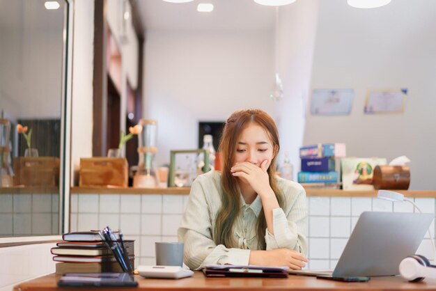 비즈니스 개념 여성 기업가는 공동 작업 공간 사무실에서 과로하는 동안 졸리고 하품을 합니다.